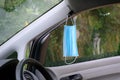 A medical protective mask hangs on the car mirror to protect against bacteria and viruses while driving. Pandemic Royalty Free Stock Photo