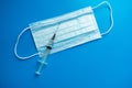 Medical protective mask syringe on a blue background. A typical 3-layer surgical mask for covering the mouth and nose.