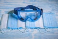 Medical protective masks and glasses on a blue wooden surface. Cavid-19 coronavirus infections