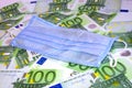 Medical protective surgical mask lies on money 100 euro banknotes. Selective focus. Price increase for face masks