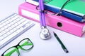 Medical record concept with stethoscope over pile of folders. Keyboard, glasses, pen, RX prescription. Selective focus Royalty Free Stock Photo