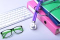 Medical record concept with stethoscope over pile of folders. Keyboard, glasses, pen, RX prescription. Selective focus Royalty Free Stock Photo