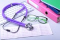 Medical record concept with stethoscope over pile of folders. Keyboard, glasses, pen, RX prescription. Selective focus Royalty Free Stock Photo