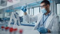 Medical Research Laboratory: Portrait of Scientist Wearing Face Mask Analysing Liquid Biochemicals