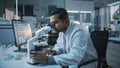 Medical Research Scientist Conducts DNA Experiments Under a Microscope and Writes Results on Deskt Royalty Free Stock Photo