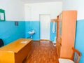 Medical room at school with a cupboard table and wash basin. blue and white walls, medical gowns on the hanger