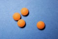 Medical round orange tablets, calcium vitamins closeup on blue background with space for text or image. Pills.