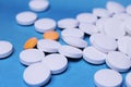 Medical round white and orange tablets, calcium vitamins closeup on blue background. Pills. Royalty Free Stock Photo