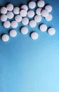 Medical round white tablets, calcium vitamins closeup on blue background with space for text or image. Pills.