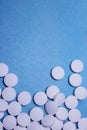 Medical round white tablets, calcium vitamins closeup on blue background with space for text or image. Pills.