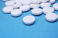 Medical round white tablets, calcium vitamins closeup on blue background with space for text or image. Pills.