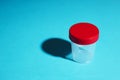 Medical sample container for clinical test. empty bottle with red cup and hard shadow over blue background. copy space