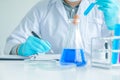 Medical science or male Compiling an Analysis Report in laboratory room research performs tests with blue liquid on test tube, Royalty Free Stock Photo