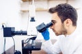 Medical scientist with microscope, examining samples and liquid in laboratory Royalty Free Stock Photo