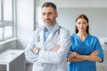 Medical services concept. Confident doctor male and female colleagues wearing coats, posing with folded arms Royalty Free Stock Photo