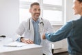 Medical services concept. Male doctor and female patient handshaking during meeting in clinic Royalty Free Stock Photo