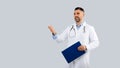 Medical services concept. Male doctor physician in uniform with clipboard in hand looking aside and talking, copy space Royalty Free Stock Photo