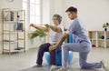Doctor helping senior patient with osteoporosis do physiotherapy exercises on fit ball