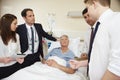 Medical Staff On Rounds Standing By Male Patient's Bed