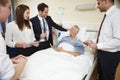 Medical Staff On Rounds Standing By Male Patient's Bed