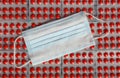 A medical sterile mask lies on the texture of the drugs.