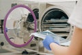 Young Female Dentist Places Medical Autoclave For Sterilising Surgical And Other Instruments. Medical Sterilizer Royalty Free Stock Photo