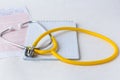 Medical stethoscope on cardiogram chart with a notepad, close up
