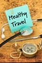 Medical stethoscope, compass and a card with the words `Healthy Travel` on the background of an old map of the world, The concept