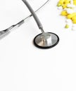 Medical stethoscope examining the heart listening to the rhythm on a white background with scattered yellow and white pills top