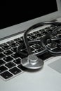 Medical stethoscope lies on the keyboard of a portable computer, part of the device screen is visible Royalty Free Stock Photo