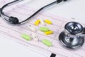 Medical stethoscope lying on cardiogram chart with pile of pills closeup. Cardiology care health protection prevention and help. H Royalty Free Stock Photo