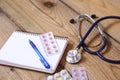 Medical stethoscope and tablets isolated on wooden background Royalty Free Stock Photo