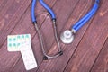 Medical stethoscope and tablets isolated on wooden background Royalty Free Stock Photo