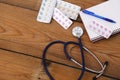 Medical stethoscope and tablets isolated on wooden background Royalty Free Stock Photo