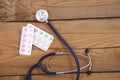 Medical stethoscope and tablets isolated on wooden background Royalty Free Stock Photo