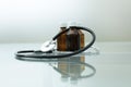 A medical stethoscope and three medicine bottles lie on a glass table