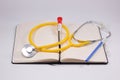 A medical stethoscope with yellow heart on notebook with blood tube, and blue pen for medicine concept Royalty Free Stock Photo