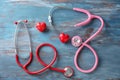 Medical stethoscopes and red hearts on wooden background. Cardiology concept