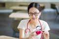 Medical student holding a magnifying glass and looks at a yarn red heart on blurred background. Royalty Free Stock Photo