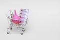 Medical suppositories in a silver blister pack and a pink rubber medical enema are placed in a toy shopping cart. Packaging of