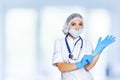 Medical surgeon doctor woman over blue clinic background. Doctor putting on sterile gloves. Place for medical advertise Royalty Free Stock Photo