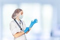 Medical surgeon doctor woman over blue clinic background. Doctor putting on sterile gloves. Place for medical advertise Royalty Free Stock Photo