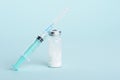 Medical syringe, glass ampoule on blue background with copy space, vaccination