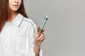 Medical syringe in the hand of a female doctor at the grey background. Young woman in medical uniform posing with a