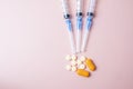 medical syringe isolated on pink background with pills