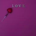 A medical syringe makes a heart and prints the word love on a pink background. Minimal scene