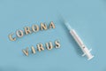 A medical syringe with a needle lies on a blue background and next to it is a coronavirus Latin script. Flu. Epidemic