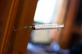 A medical syringe stuck in a varnished wooden board