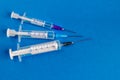 Medical syringes of different capacities lie on a blue surface