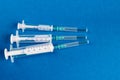 Medical syringes of different capacities lie on a blue surface